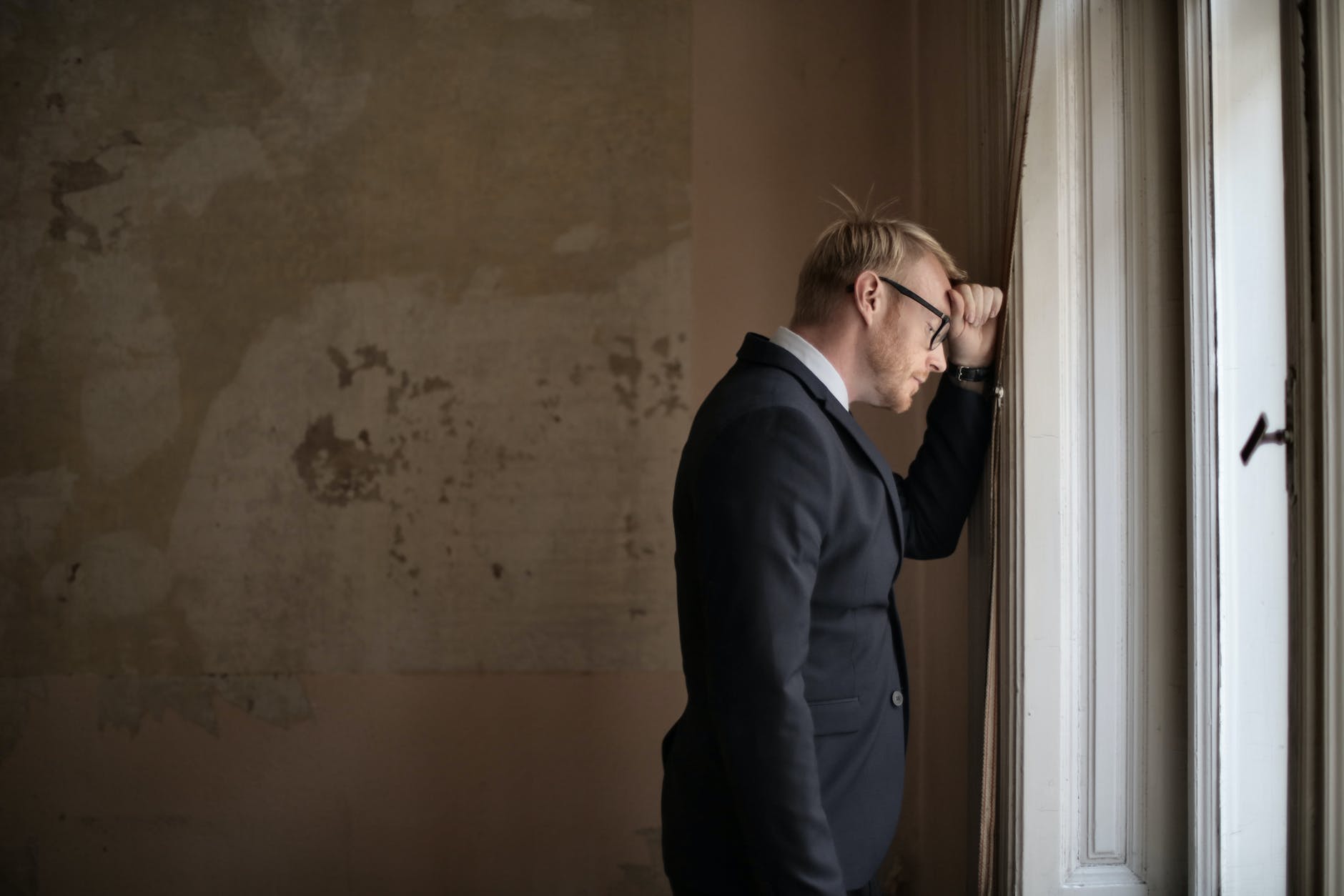 managing difficult emotions -- desperate evicted male entrepreneur standing near window